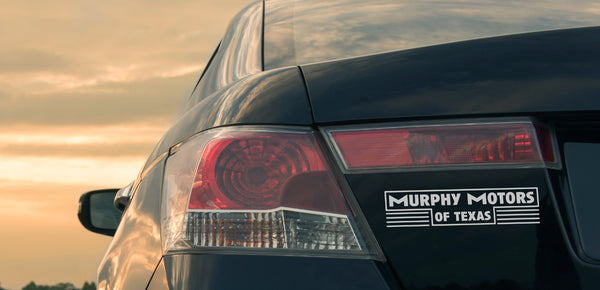 Pro-cut vinyl dealer decal on a vehicle trunk at sunset