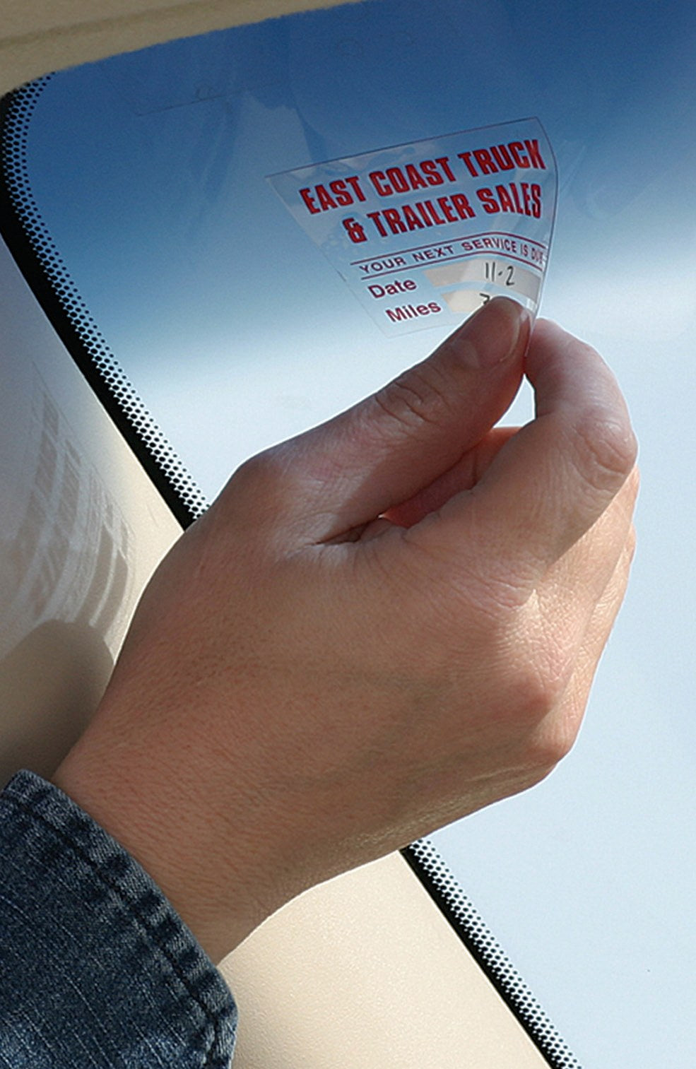 Static stick service reminder cling being applied to a windshield